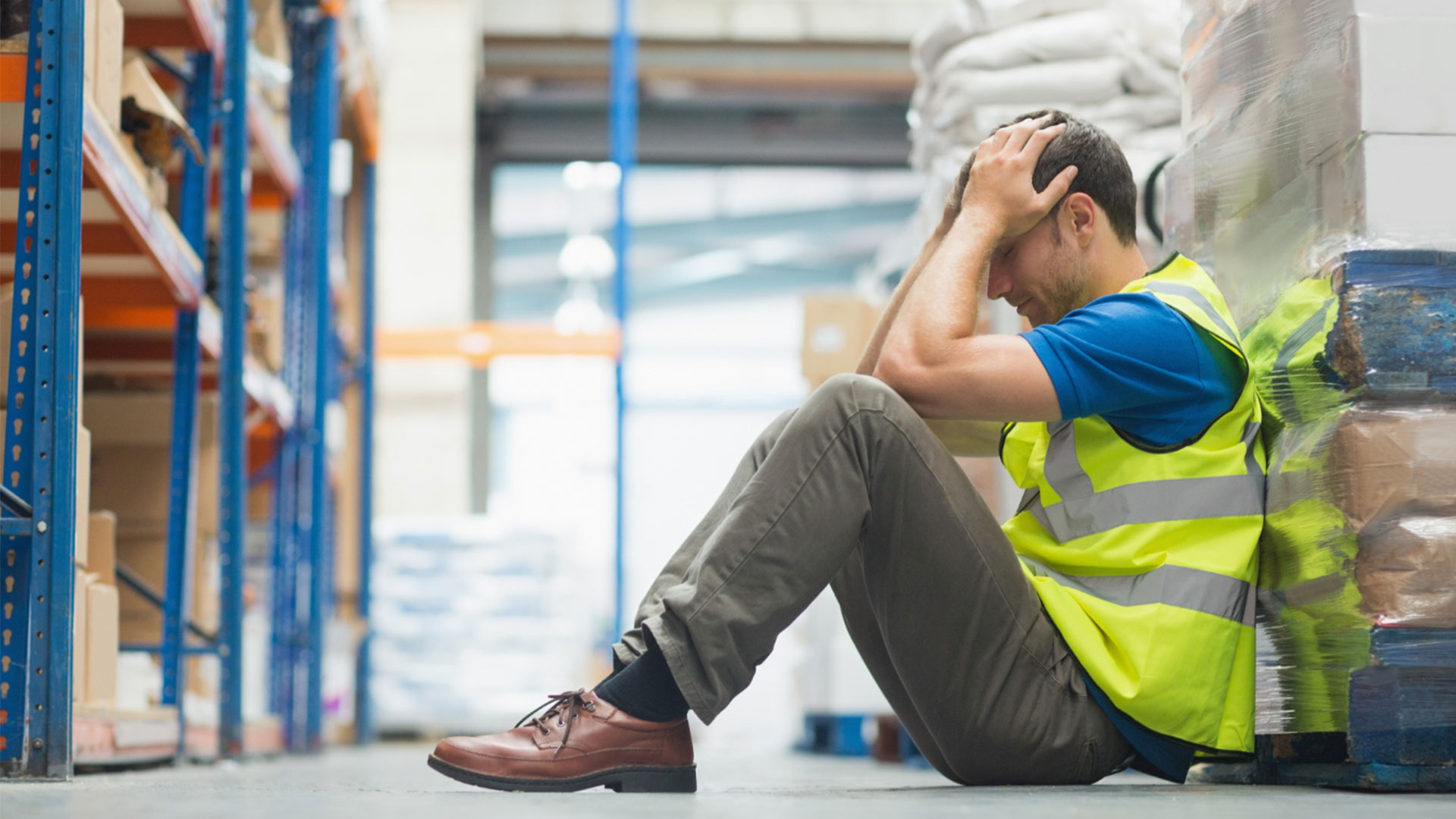 Man sitting on warehouse floor with head in hands